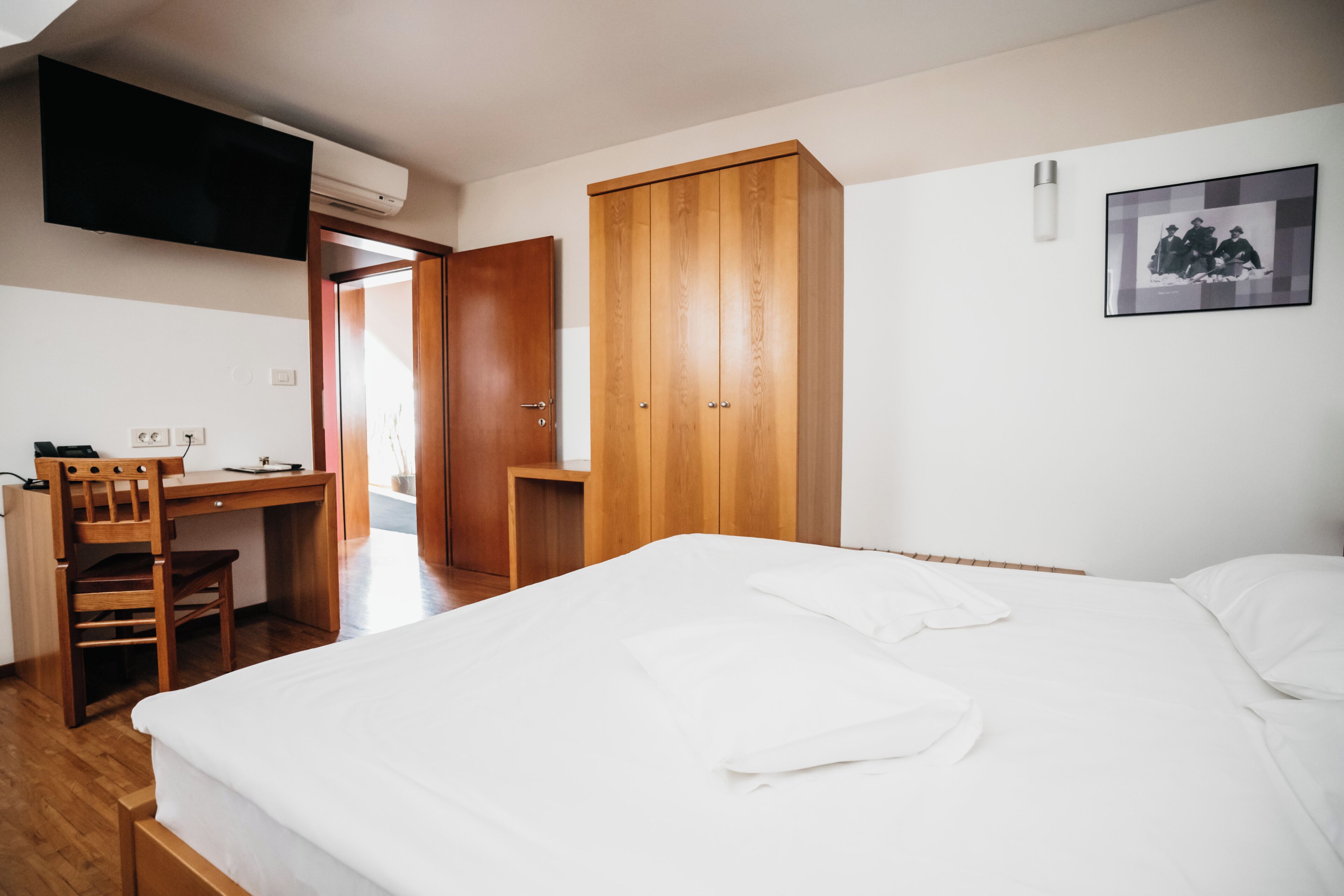 A bedroom with a bed, a desk, and a wardrobe.