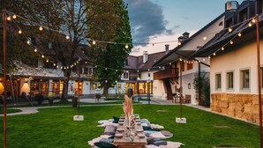 An outdoor dining area with a long table set for a meal, surrounded by cushions and a decorative centerpiece. - Dvor Jezeršek Brnik (Cerklje na Gorenjskem)