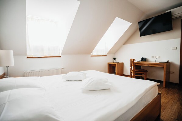 A hotel room with a large bed, a desk, and a TV mounted on the wall.