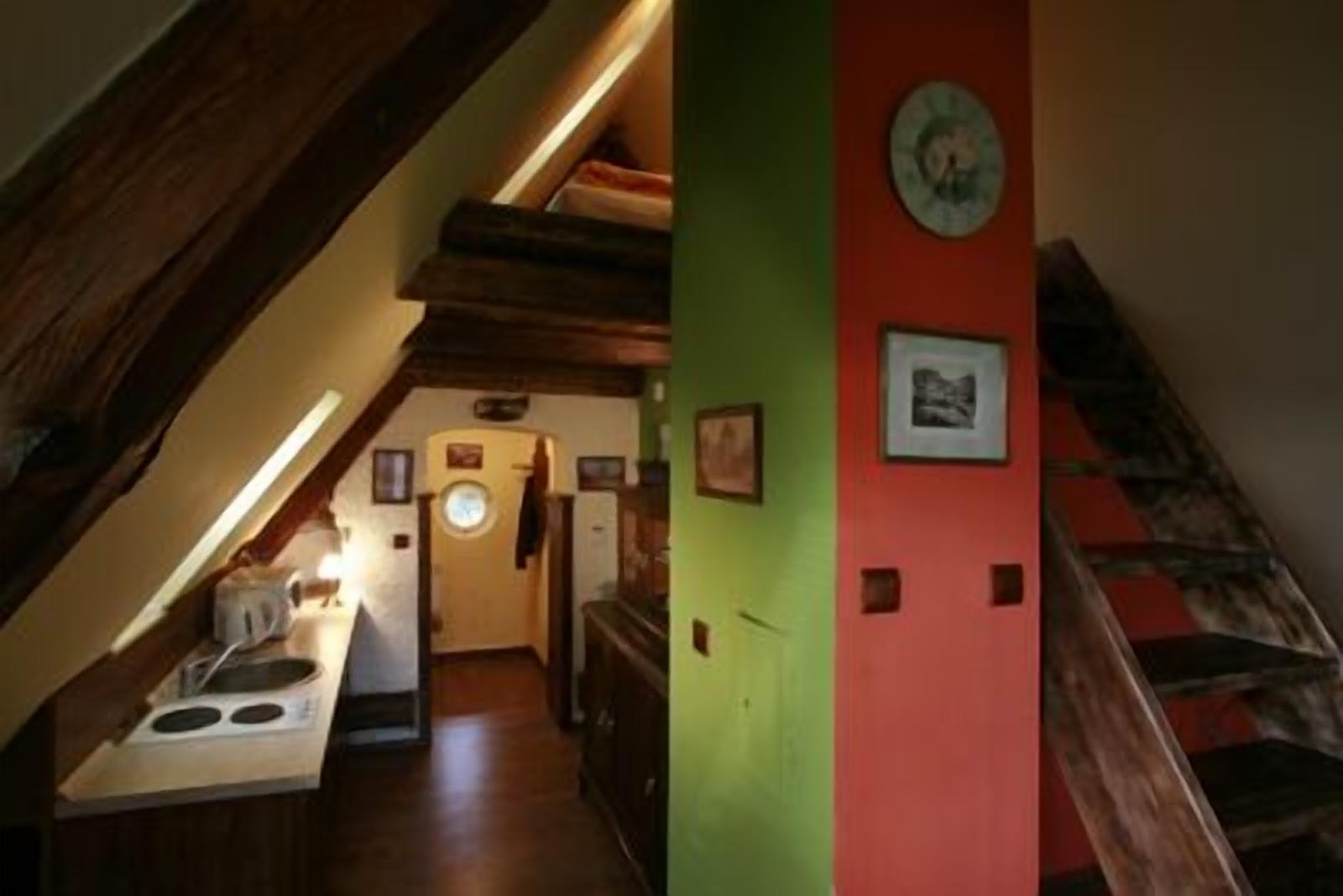 Un pasillo estrecho con una escalera de madera a un lado y una zona de cocina al otro.