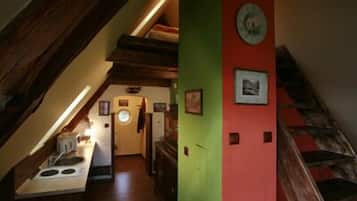 Un pasillo estrecho con una escalera de madera a un lado y una zona de cocina al otro.