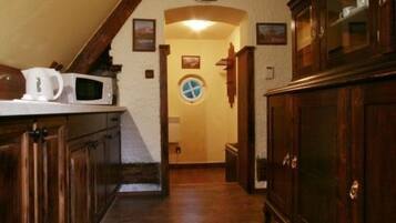 A narrow hallway with wooden cabinets and a microwave on the left.