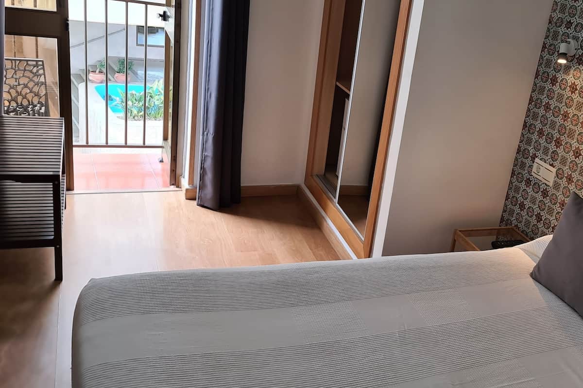 Un dormitorio con cama, ventana, pared estampada y vistas a un espacio exterior.
