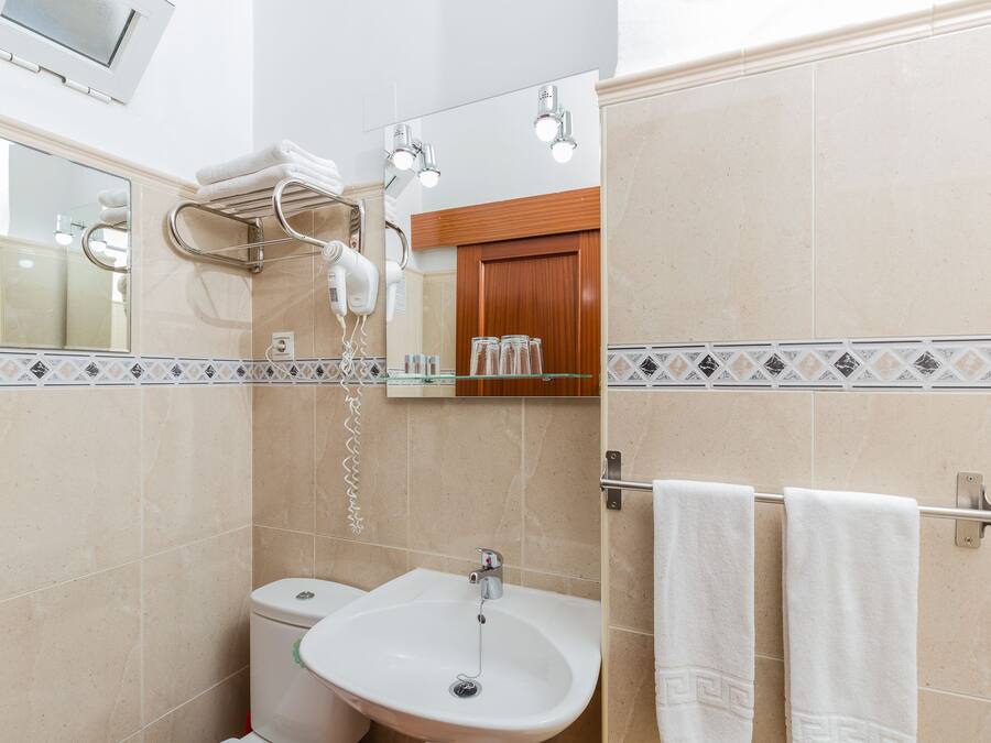 Een badkamer met een wastafel, toilet en handdoekrek.