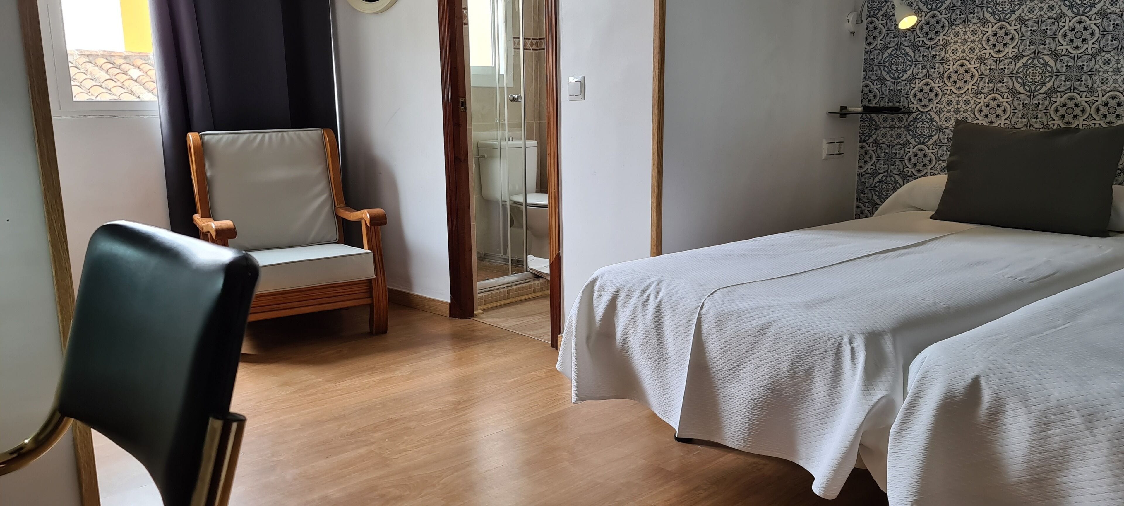 Een hotelkamer met een bed, een stoel en een douche.