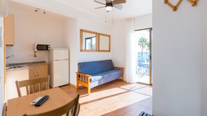 A compact living space with a kitchenette, a sofa, a dining table, and a ceiling fan. - Hostal Guadalupe (Torremolinos)
