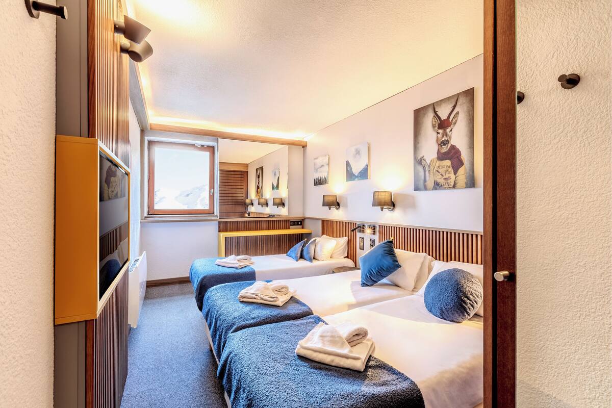 Een hotelkamer met twee bedden, een houten hoofdbord, een grote spiegel en kunst aan de muur.