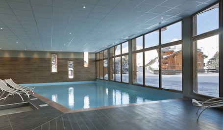 Una piscina techada, sillones reclinables de piscina