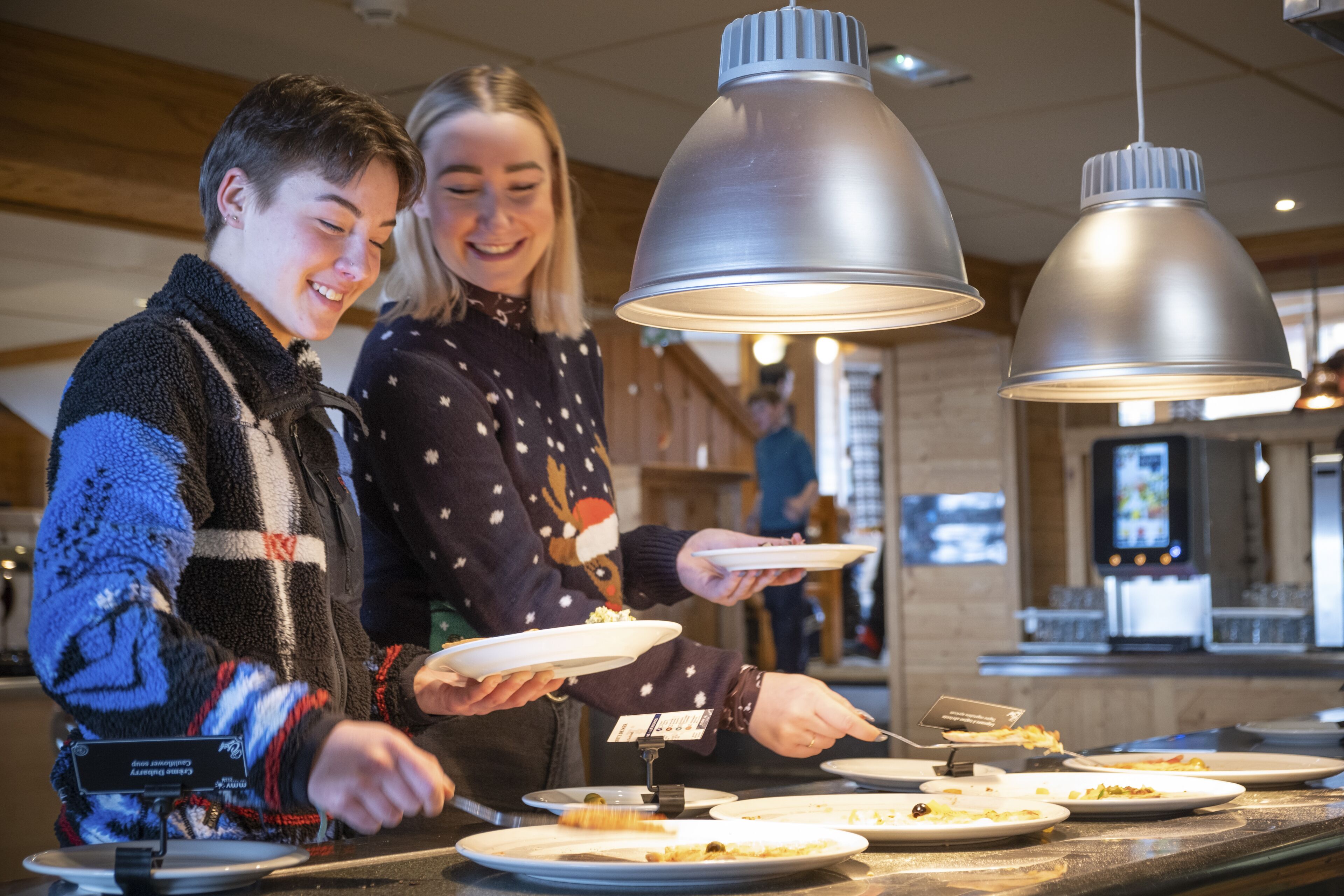 Zona de buffet amb nombrosos plats de menjar, una caixa registradora i il·luminació penjant.
