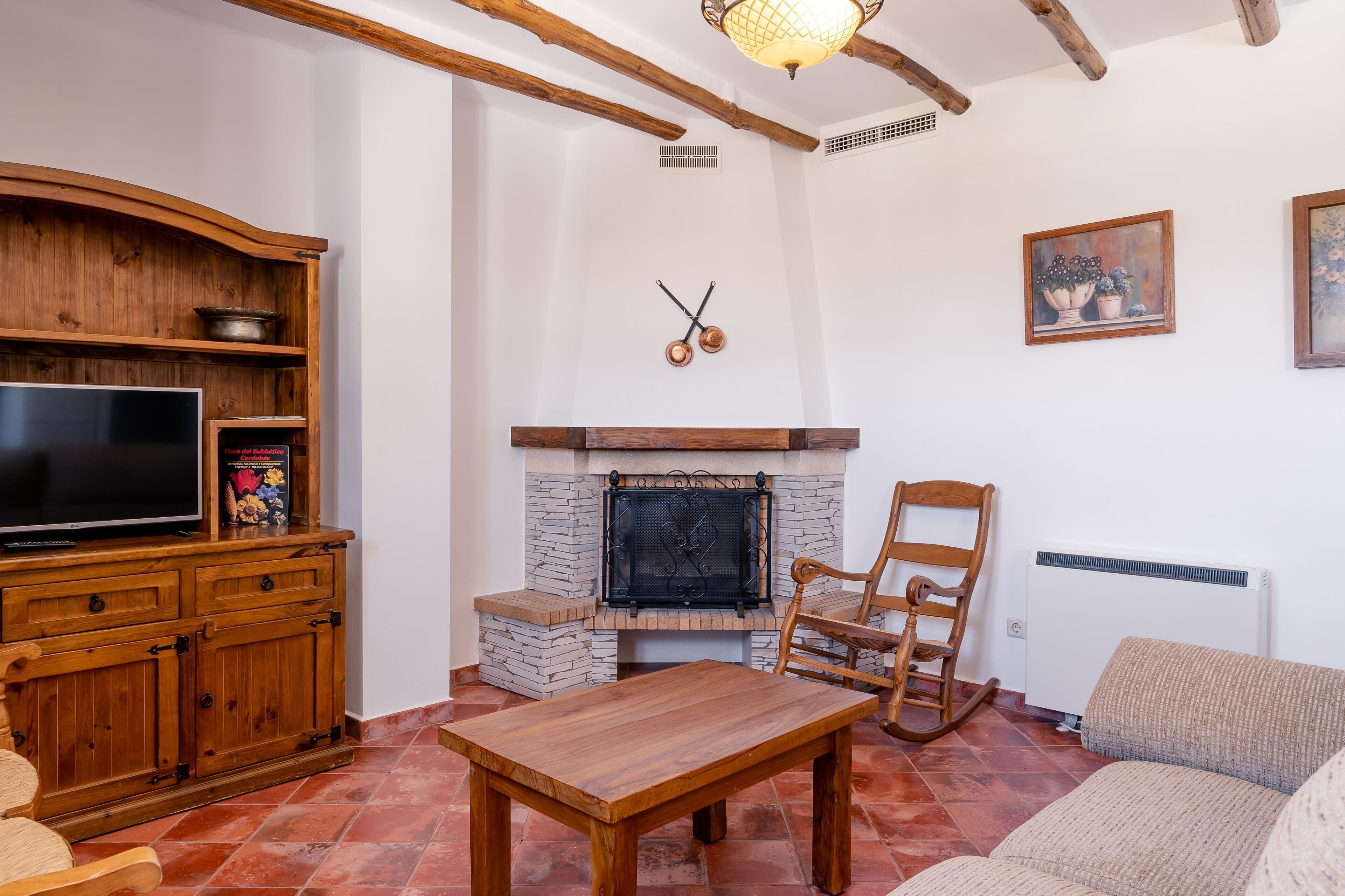 A living room with a fireplace, wooden furniture, a television, and a painting on the wall.