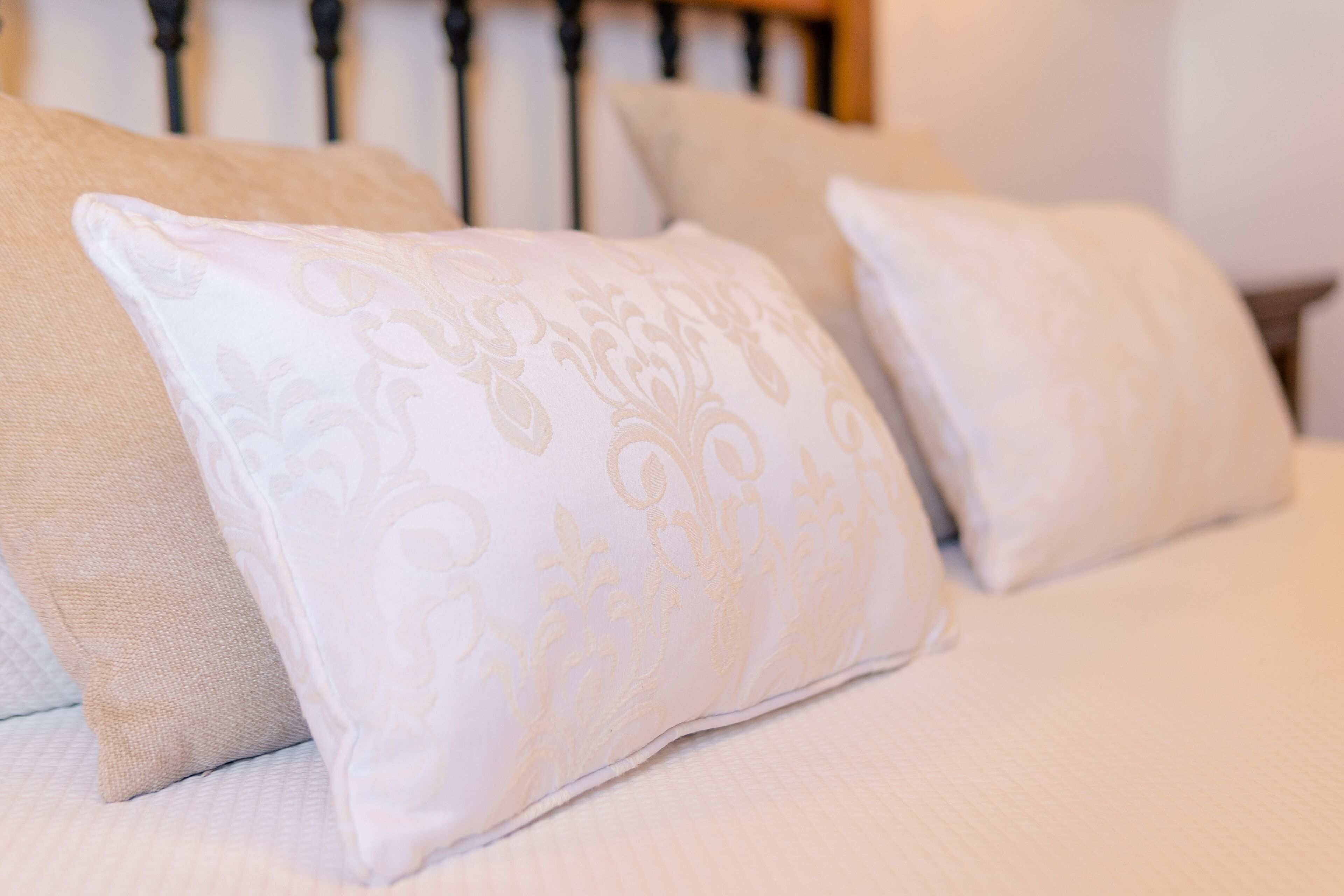 A bed with beige bedding and decorative pillows.