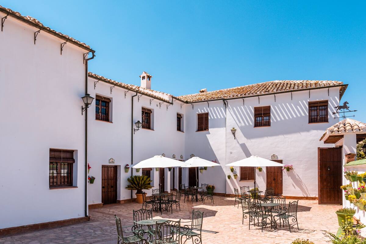 A courtyard with outdoor seating, white walls, and tiled roofs.