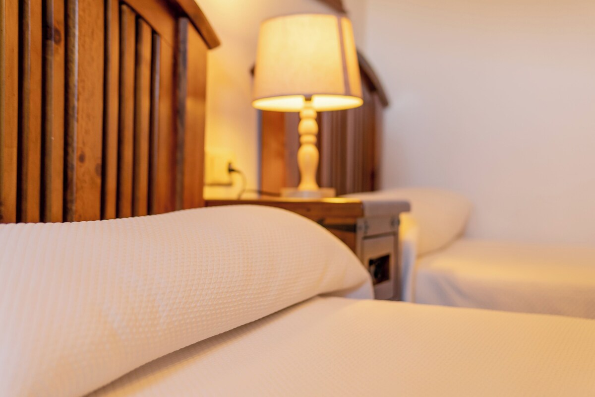 Primer plano de una cama con ropa blanca y cabecera de madera.