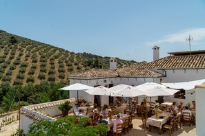 An outdoor patio with tables and chairs, surrounded by white walls and a tiled roof. - Cortijo La Presa (Priego de Córdoba)