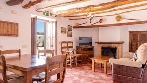 A rustic interior with a wooden dining table, chairs, a sofa, and a television. - Cortijo La Presa (Priego de Córdoba)