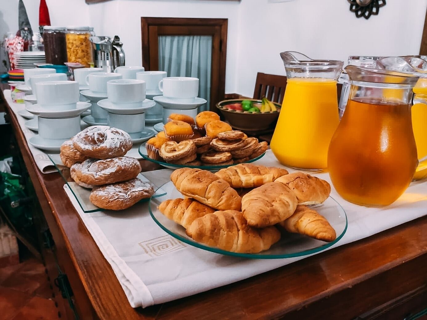 A breakfast buffet with pastries, coffee cups, and orange juice.