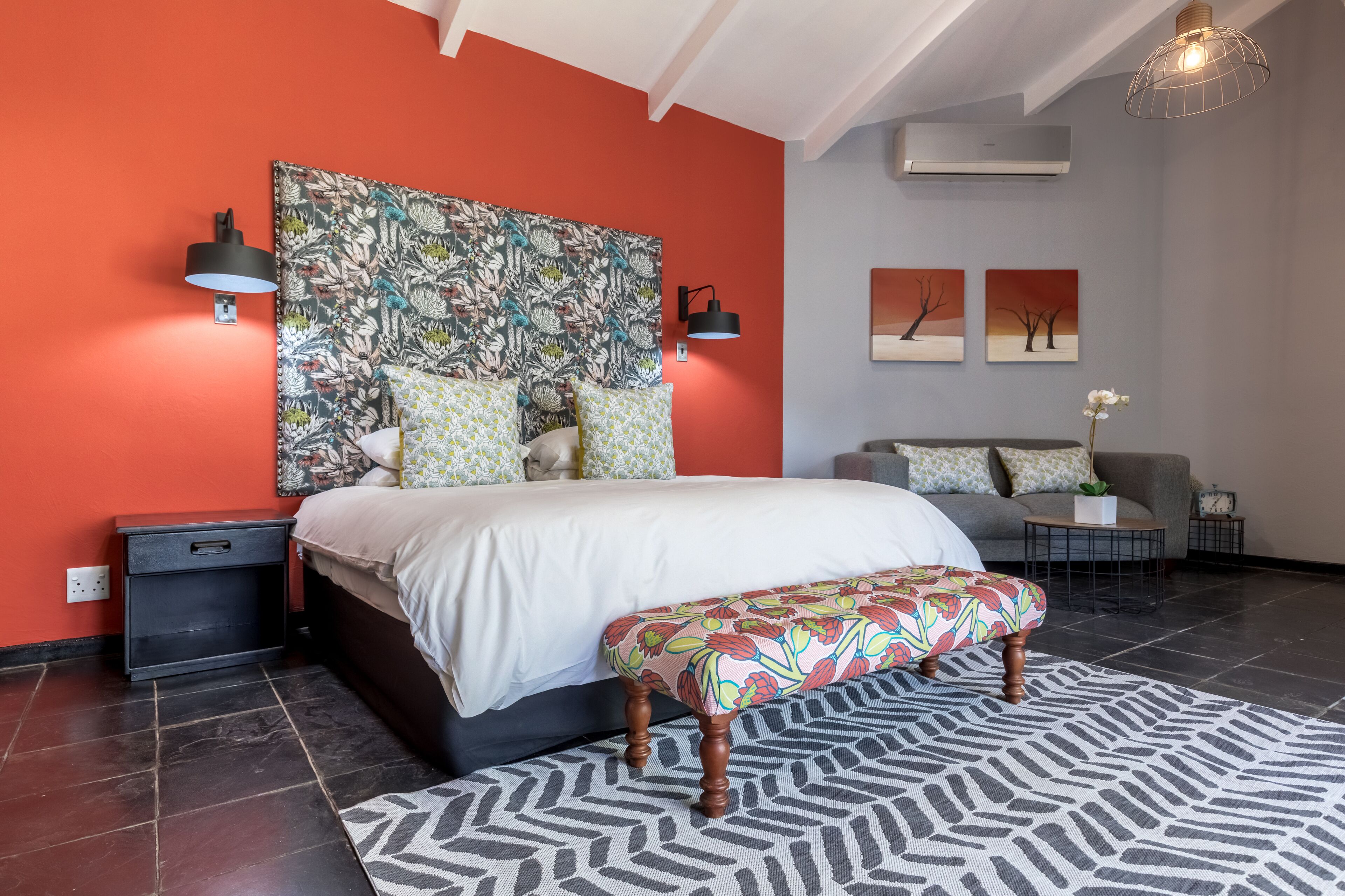 A modern bedroom with a large bed, a bench, a sofa, and a coffee table.