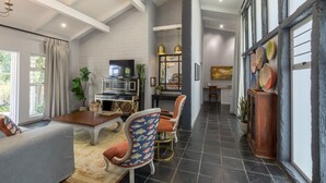 A spacious living area with a high ceiling, a fireplace, and a dining area with a view of the outdoors. - La Roca Guest House (Mbombela)