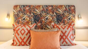 A bed with a patterned headboard, two wall-mounted lights, and multiple pillows.