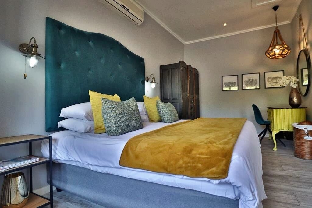 Un dormitorio con una cama grande, un cabecero oscuro, una manta amarilla y un armario de madera.