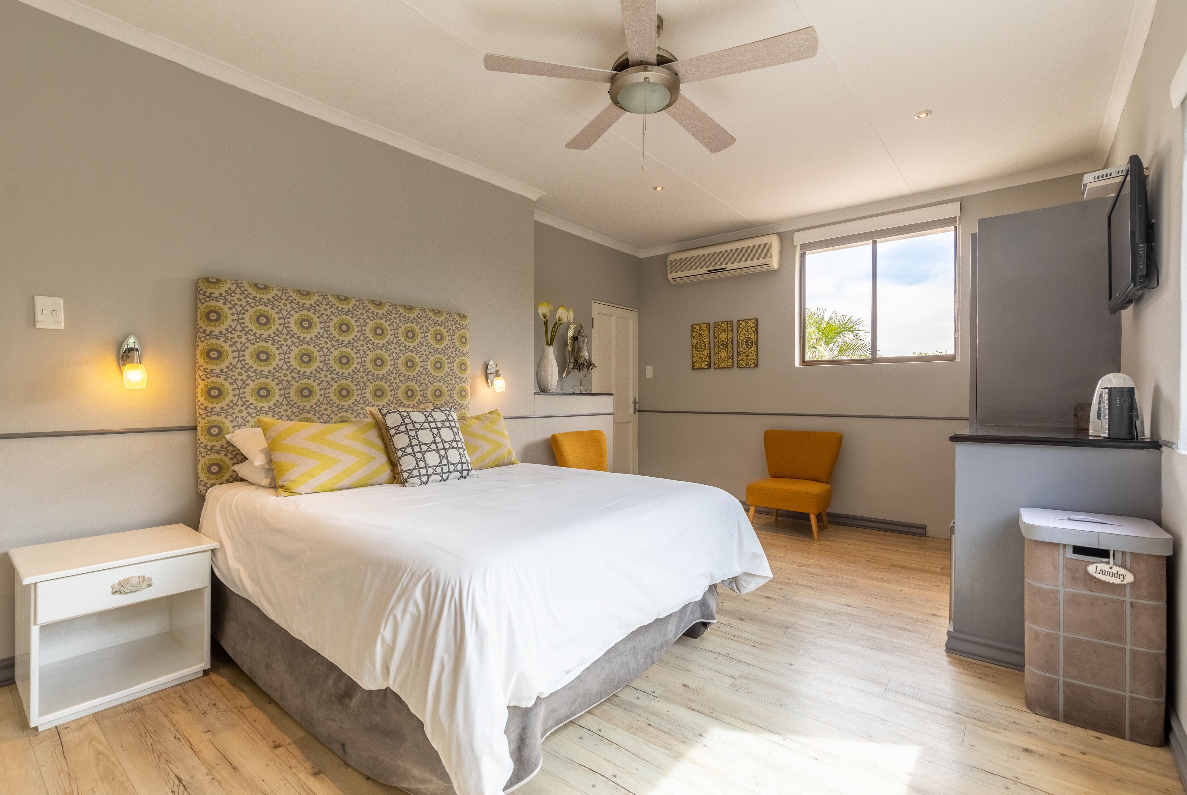 Une chambre à coucher comprenant un lit, une table de chevet, un téléviseur fixé au mur, un appareil de climatisation et une fenêtre avec vue.