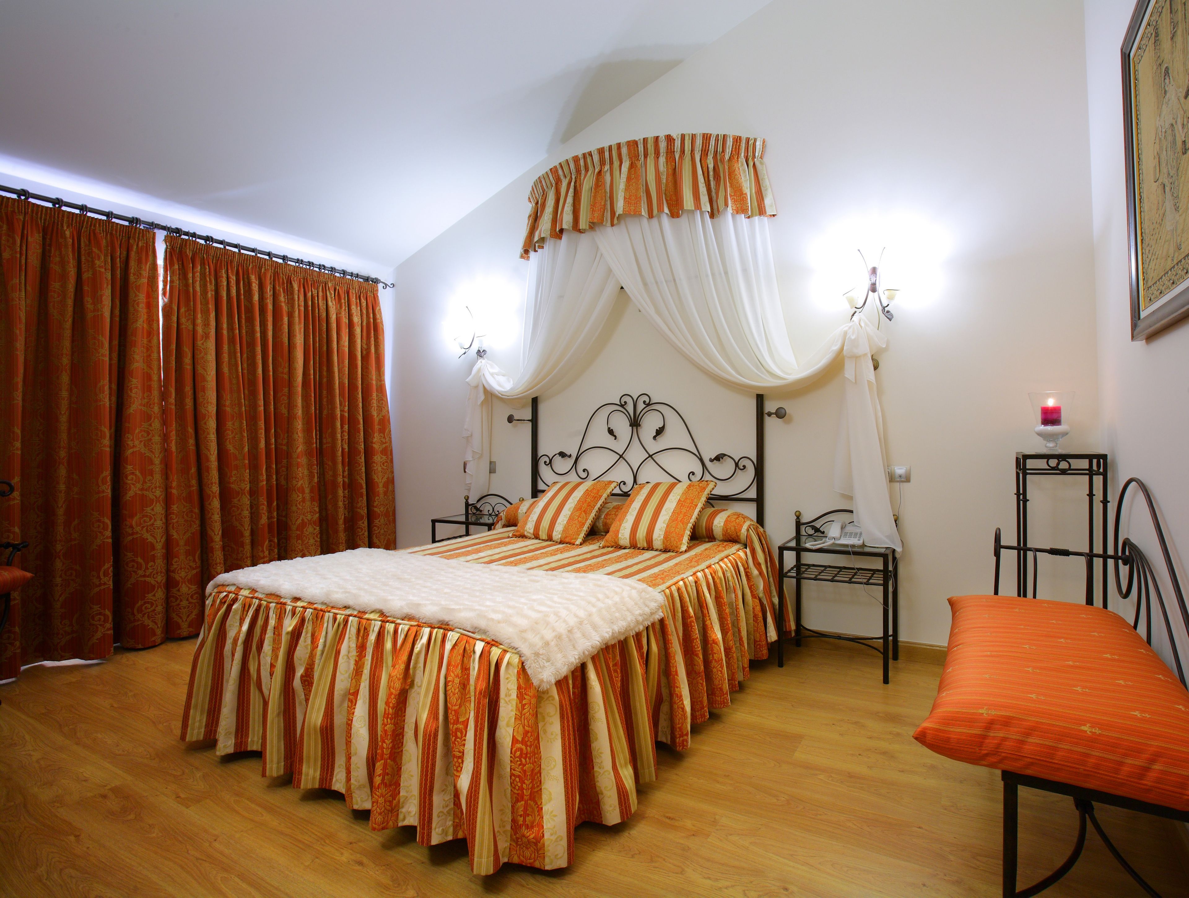 A bedroom with a bed, curtains, a bedside table, a lamp, and a chair.