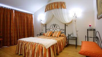 A bedroom with a bed, curtains, a bedside table, a lamp, and a chair.