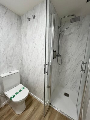 A bathroom with a toilet, a glass-enclosed shower, and marble walls. - IRAIPE GORBEA HOTEL (Vitoria-Gasteiz)
