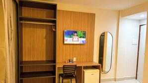 A hotel room with a wooden wardrobe, a small desk with a chair, a television mounted on the wall, and a mirror. - EL ARAM PONTA NEGRA (Natal)