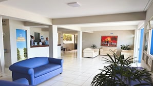 Un hall d’entrée spacieux avec un canapé bleu, un comptoir d’accueil et un tableau accroché au mur.