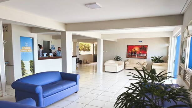 A spacious lobby with a blue sofa, a reception desk, and a painting on the wall. - EL ARAM PONTA NEGRA (Natal)