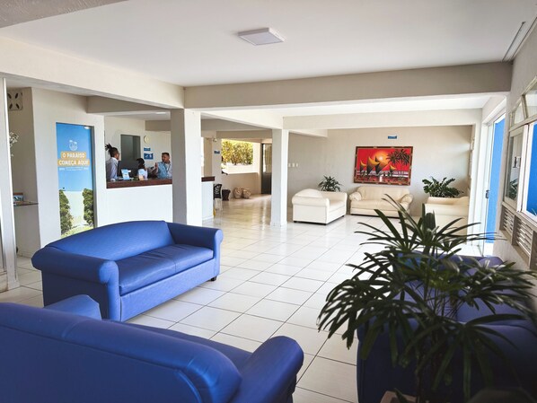 A spacious lobby with a blue sofa, a reception desk, and a painting on the wall. - EL ARAM PONTA NEGRA (Natal)