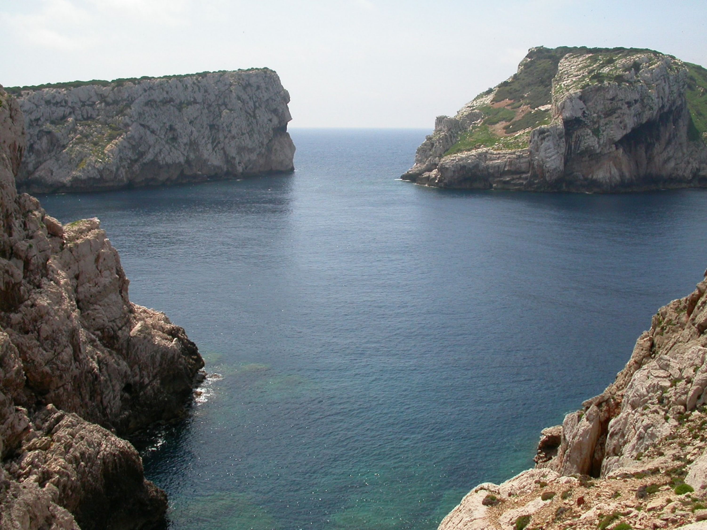 Un paisaje costero con acantilados rocosos y un mar en calma.