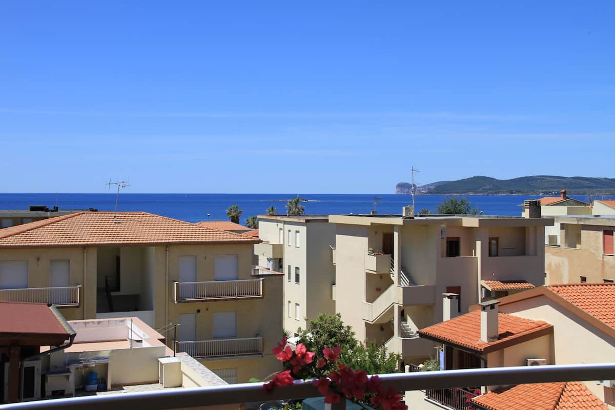 A coastal residential area with buildings featuring balconies and a clear view of the sea.