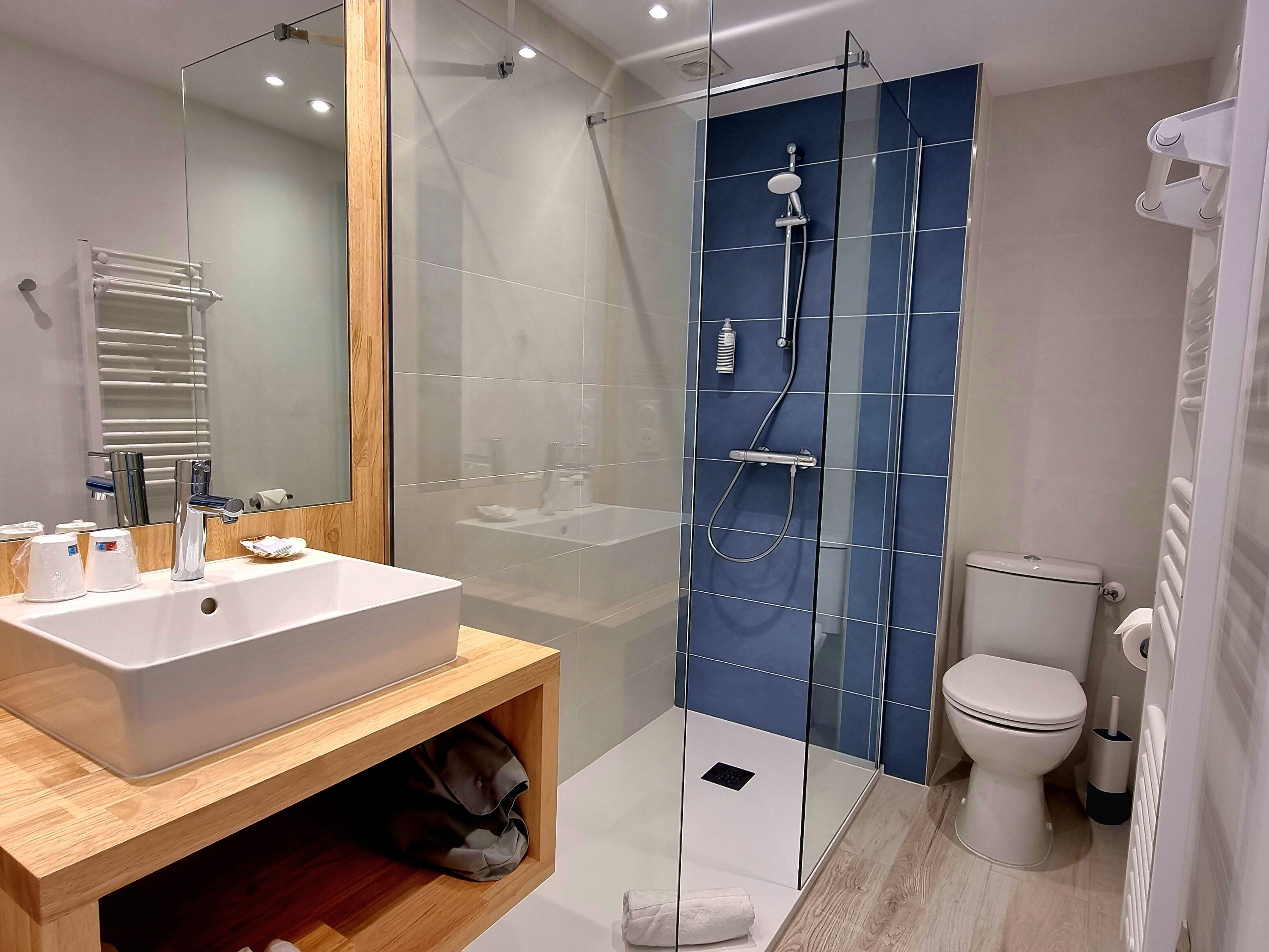 Un baño moderno con ducha envuelta en vidrio, lavamanos blanco y retrete.