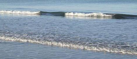 Uma praia com ondas suaves batendo na costa.