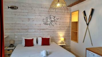 A hotel room with a wooden wall, a bed with white and red pillows, a bedside lamp, and a fish decoration.