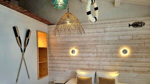 Een slaapkamer met een houten wand, twee bedlampen, een bed met witte en bruine kussens en een hangende lamp.
