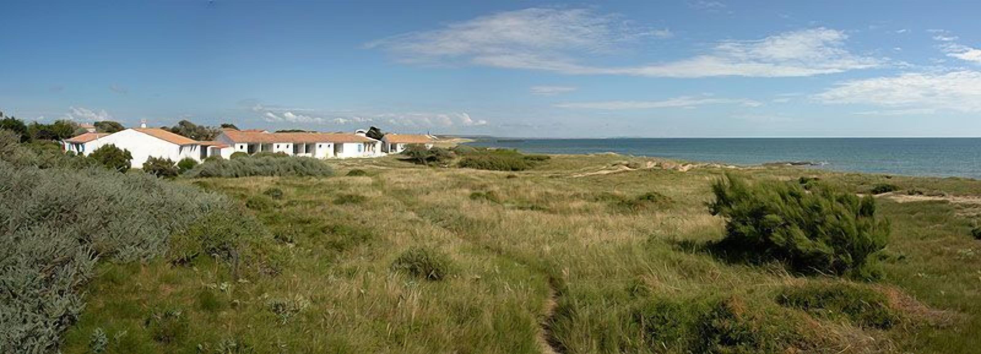 A coastal property with white buildings and a grassy landscape.
