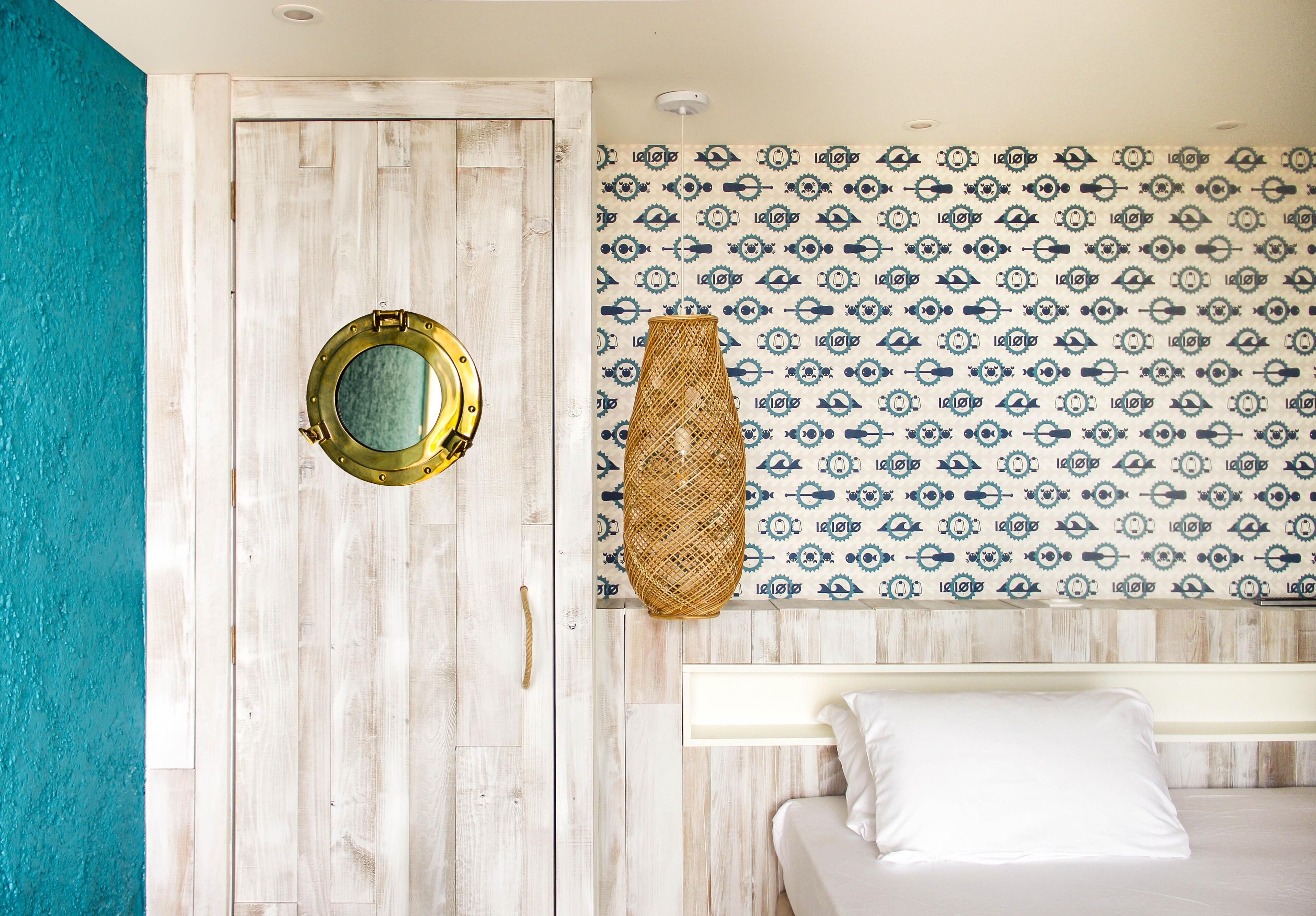 A room with a wooden door, a bed with white bedding, and a patterned wall.