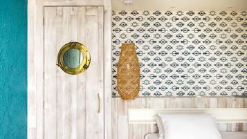 A room with a wooden door, a bed with white bedding, and a patterned wall.