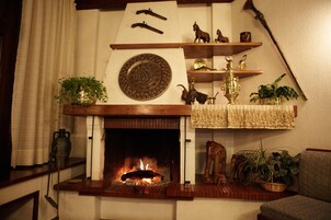 Una chimenea con fuego, rodeada de estantes con adornos y plantas.