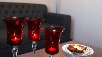 Tre röda ljusstakar står på ett bord, en skål med ett ljus och en röd lampa syns i bakgrunden.