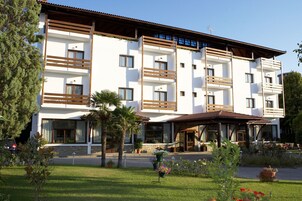 Un hotel de varios pisos con balcones, una entrada cubierta y un jardín bien cuidado.