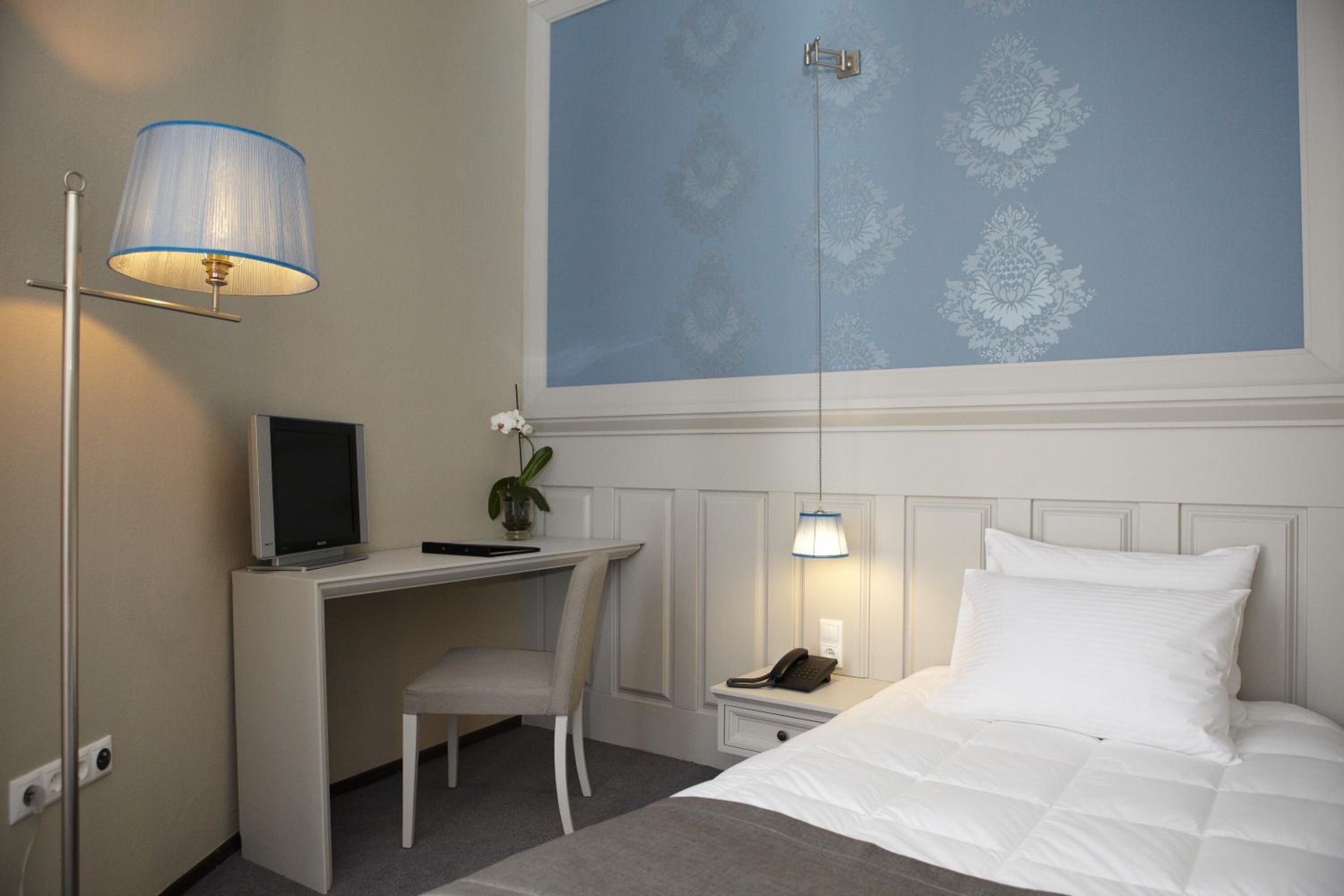 Ein Hotelzimmer mit Bett, Schreibtisch, Stuhl und zwei Nachttischlampen.