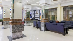 A hotel reception area with a marble reception desk, blue sofas, and a large mirror. - Salita Hotel (Phnom Penh)