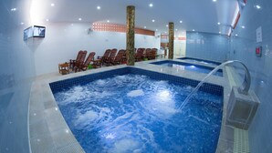 A swimming pool with a hot tub, wooden chairs, and a tiled wall. - Salita Hotel (Phnom Penh)