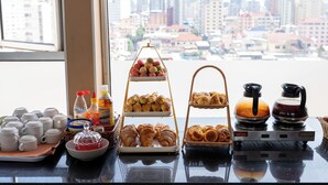 A breakfast buffet with pastries, coffee, and tea, set against a cityscape view. - Salita Hotel (Phnom Penh)