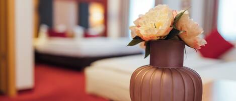 Un vase rempli de fleurs est posé sur une table dans une chambre d’hôtel.