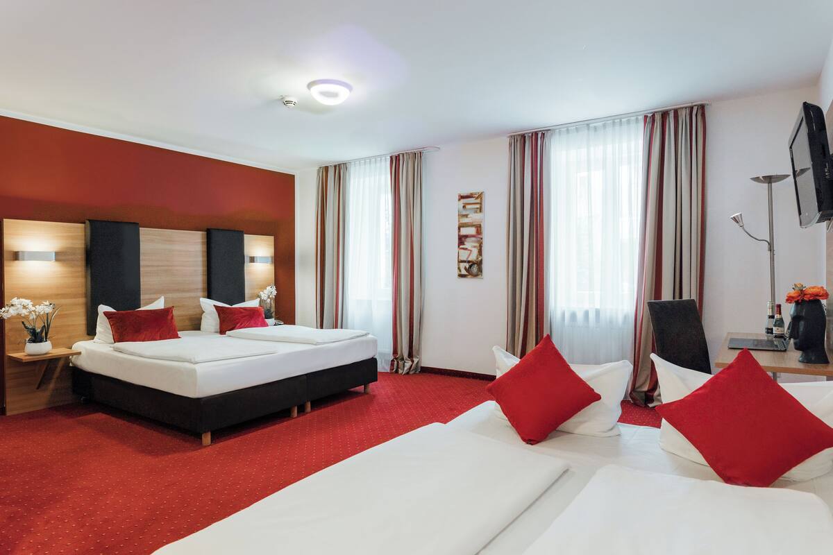 Hotellihuone, jossa on suuri sänky, sohva, työpöytä ja televisio.